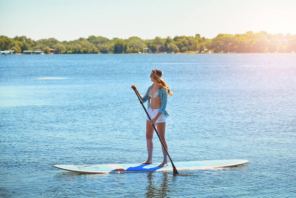 Flutuando em águas calmas. uma atraente jovem mulher remo embarque em um lago - Foto, Imagem