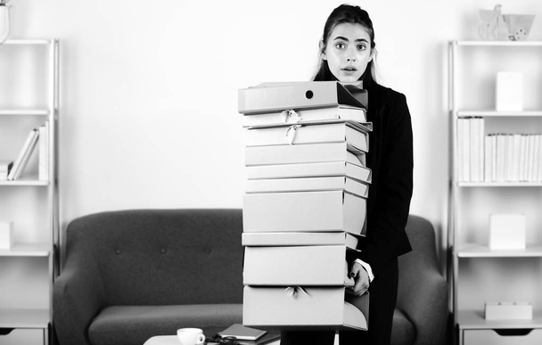 Sad secretary girl, stressed overworked businesswoman too much work, office problem. Tired stressed young woman employee holding many folders with the documents - Foto, Bild