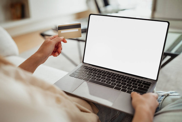 Milenyum Avrupalı kadın bilgisayarda boş ekranla yazı yazıyor, oturma odasının içinde kredi kartı kullanıyor. İndirim, evde online alışveriş için web sitesi, satın alma düzeni için aygıt, finans uygulaması - Fotoğraf, Görsel