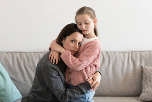 Розчарована сумна мама, яка обіймає маленьку дівчинку, заспокоює жінку у вітальні. Допомога, підтримка, любов і споріднення вдома, проблеми й пригнічення - Фото, зображення
