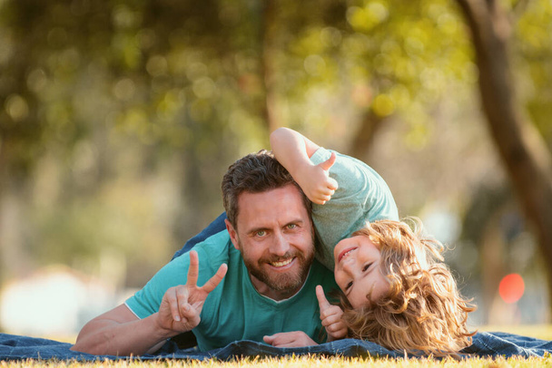 Father and son relaxing on nature in park. Happy dad and child enjoying summer time on vacation in park - Фото, изображение