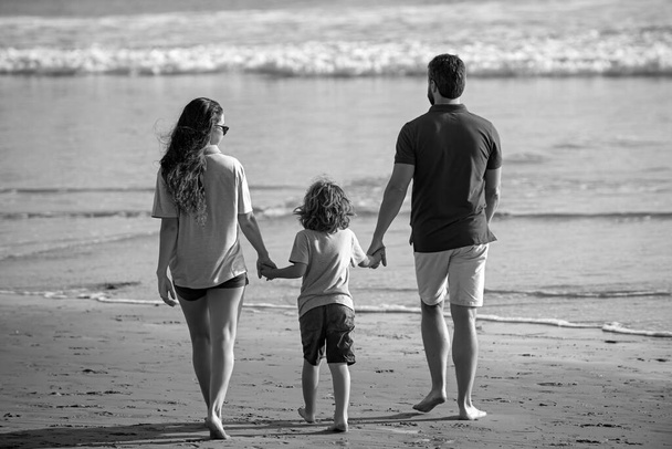 Back view of young happy family on the beach vacation - Фото, зображення