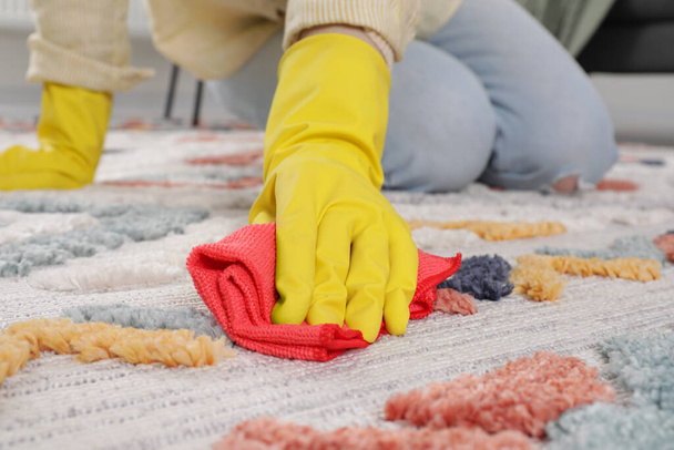 Woman in rubber gloves cleaning carpet with rag indoors, closeup - Foto, Imagen