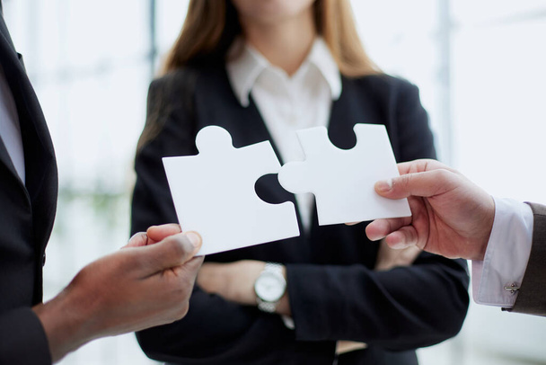 Group of business people assembling jigsaw puzzle and represent team support and help concept - 写真・画像