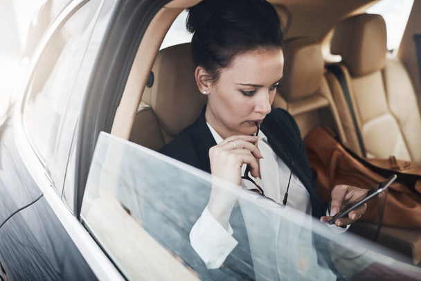 Схоже, це зайнятий графік сьогодні. впевнена молода бізнес-леді сидить в машині як пасажир під час смс на її телефоні на її шляху до роботи
 - Фото, зображення