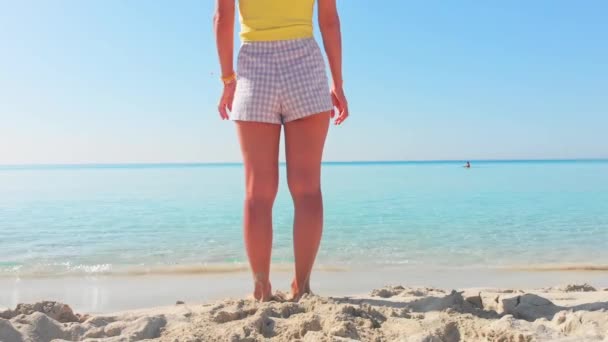 Back view beautiful young woman stand on Nissi beach in Cyprus enjoy sea view on holiday vacation in summer outdoors. Blue sky and white sand beach with clear mediterranean waters - Footage, Video