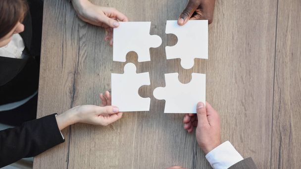 Diverse team people assembling jigsaw puzzle, multiracial group of black and white colleagues engaging in succes - 写真・画像