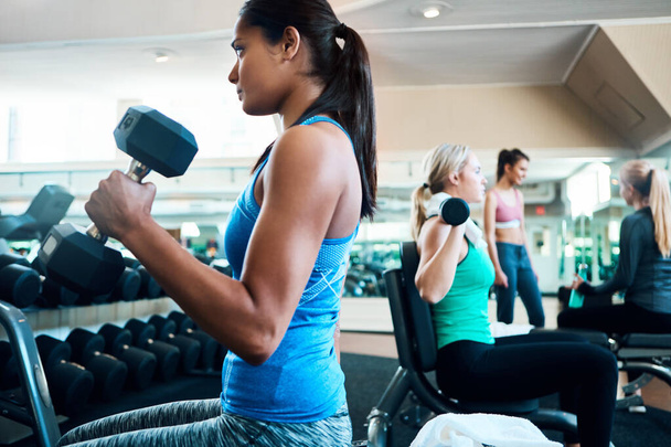 Taking her workout to another level. attractive young women working out with dumbbells at the gym - 写真・画像
