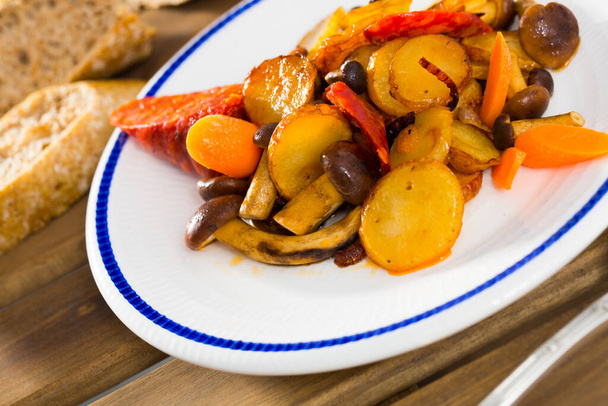 Delicious cooked fried potatoes with honey fungus mushrooms and sausage - Foto, Imagen