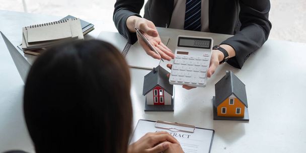Agentes inmobiliarios hablan con el cliente y ofrecen buenas tasas de interés y calculan los clientes sobre la financiación hipotecaria - Foto, Imagen