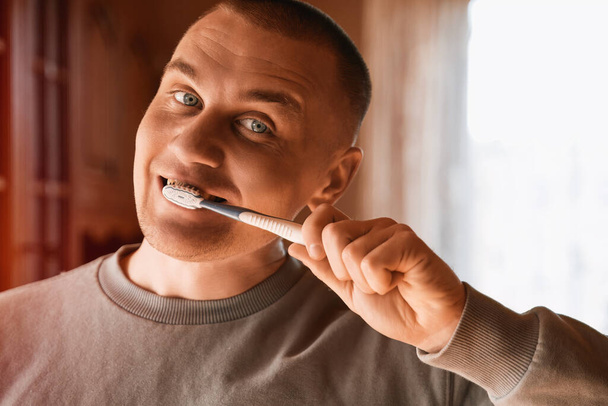 Portrait of a man with blue eyes cleaning teeth - 写真・画像