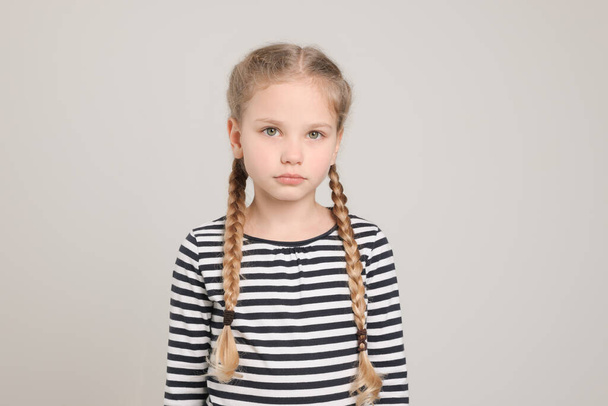 Little girl on light grey background. Children's bullying - Foto, Imagem