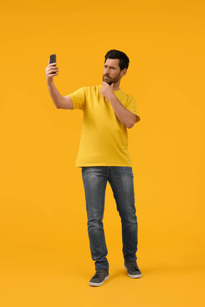 Man taking selfie with smartphone on yellow background - Фото, изображение