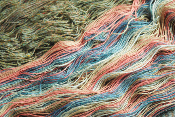 Fäden aus natürlicher Bio-Schafwolle. Zwei abgewickelte Knäuel aus grünen und regenbogenfarbenen Strickgarnen. - Foto, Bild