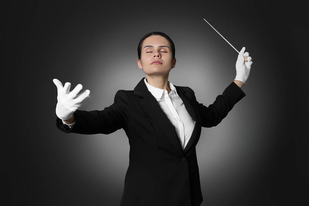 Professional conductor with baton on black background - Foto, afbeelding