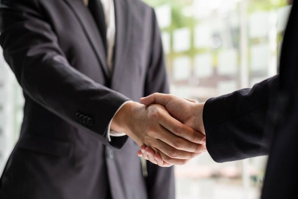 Two businessmen are shaking hand in the office room. congratulation, greeting and dealing concept. - Zdjęcie, obraz