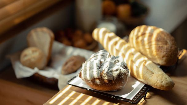 Baguette recién horneado y pan de masa fermentada en la mesa de madera. Alimentación saludable y concepto de panadería tradicional. - Foto, imagen