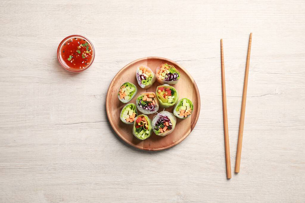 Tasty spring rolls, chopsticks and sauce on white wooden table, flat lay - Foto, afbeelding