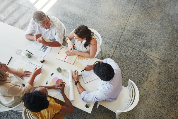 Taking business ideas to new heights. High angle shot of a team of businesspeople having a meeting around a table in their office - Foto, Imagen