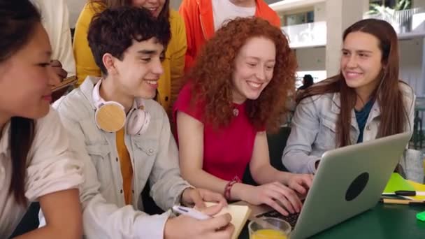 Jonge groep studenten die samen studeren op de campus. Middelbare school millennial tiener klasgenoot werken aan laptop zittend aan cafetaria tafel. Onderwijsconcept. - Video