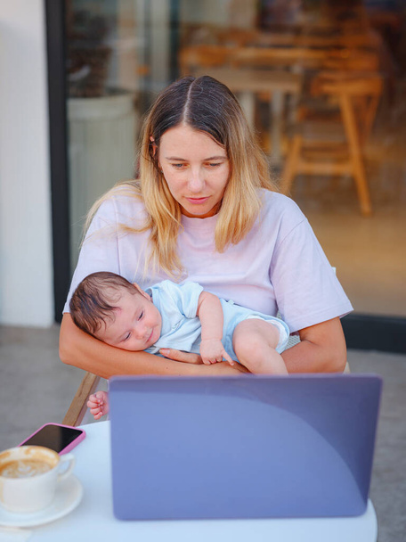 Diverse mensen portretteren. Creatieve zakenvrouw balanceert werk en moederschap. Mooie jonge moeder werken met laptop computer en borstvoeding, holding en verpleging van haar pasgeboren baby in cafe. - Foto, afbeelding