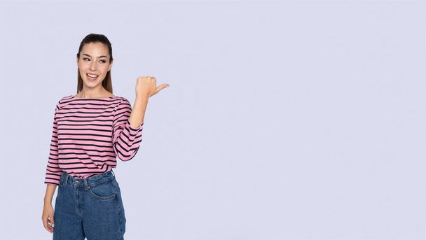 Great offer. Emotional happy attractive young hispanic woman wearing casual outfit pointing with thumb at copy space for text or advertisement over grey studio background, panorama - Φωτογραφία, εικόνα