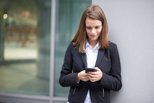 Smiling businesswoman using a smartphone outdoor - Photo, Image