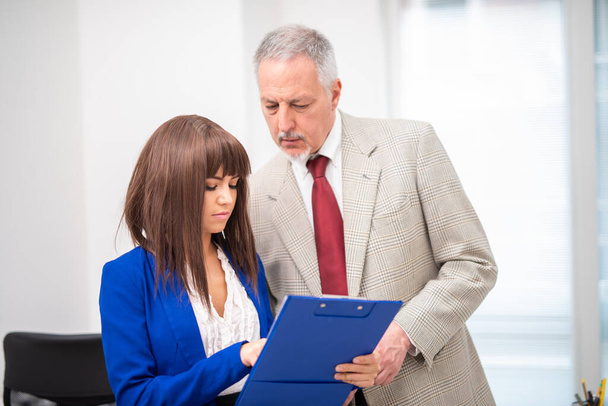 Businesswoman showing document to an elder colleague - Фото, изображение