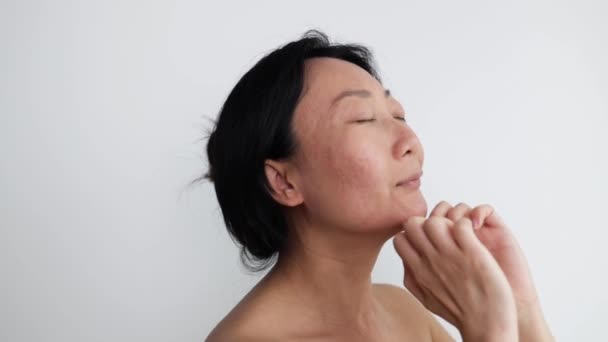 Genç Asyalı kadın yüz geliştirme jimnastiği yapıyor kendine masaj yapıyor ve çeneye dokunarak canlandırıcı egzersizler yapıyor. - Video, Çekim