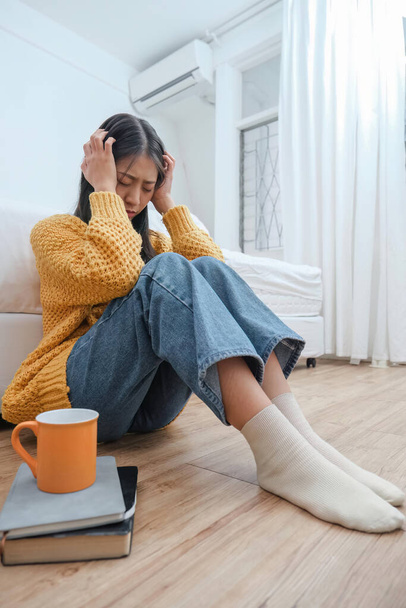 いらいらする病気の女性の閉じる床に座る頭痛片頭痛の痛みは、家のリビングルームで健康上の問題が近い目を持っています. - 写真・画像