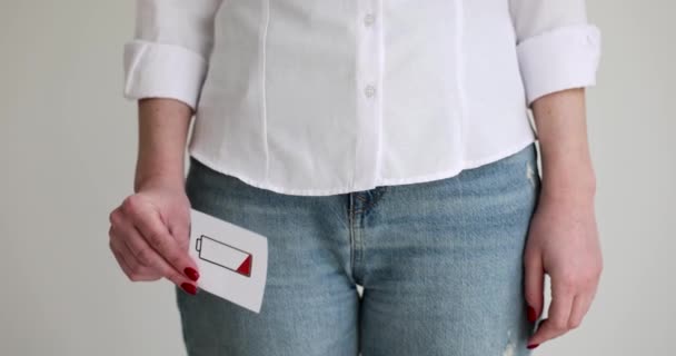 Mujer sosteniendo signo de batería baja a sus genitales primer plano 4k película cámara lenta. Disminución de la libido en el concepto de mujeres - Imágenes, Vídeo