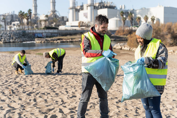 Group of people working together to clean industrial waste in river sea shore - Foto, Imagen