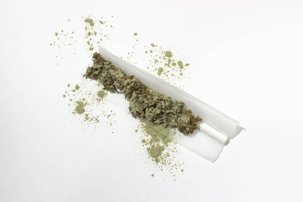 Raw joint sprinkled with kief on a white background.  Crushed buds of medical marijuana in roll-up paper, filter - Photo, Image