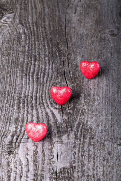 Τρία λαμπερά κόκκινες καρδιές σε παλιά ξύλινη φόντο - Φωτογραφία, εικόνα