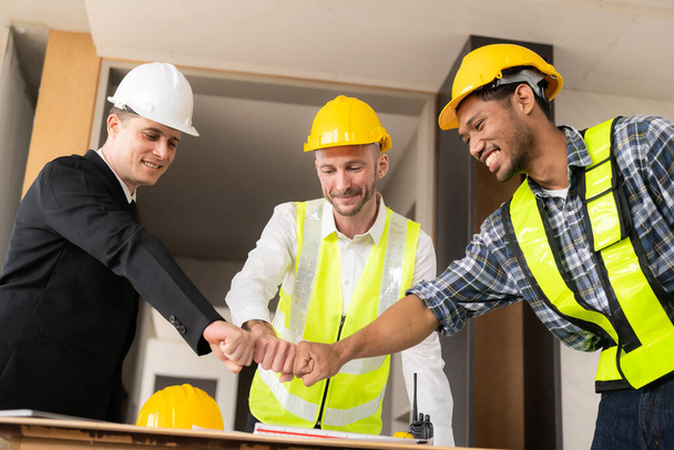 オフィス建設現場での合意後にチームワークと協力のコンセプトで作業中に握手をする建築家と建設労働者のエンジニア. - 写真・画像