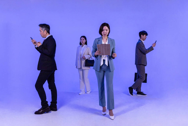 Asian Korean senior, middle aged and young male and female colleagues models in business attire, neon purple studio background, go separate ways concept - Zdjęcie, obraz
