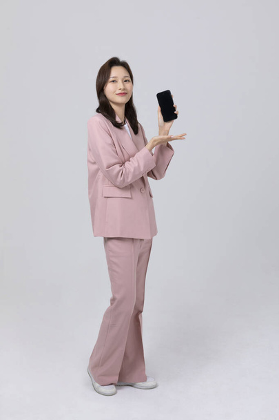 business concept korean young woman, holding a smartphone. studio shot - Foto, afbeelding