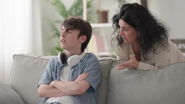 vrouw geven advies aan zoon en de tiener jongen negeren haar op de hoofdtelefoon en beginnen te videospel spelen - Video