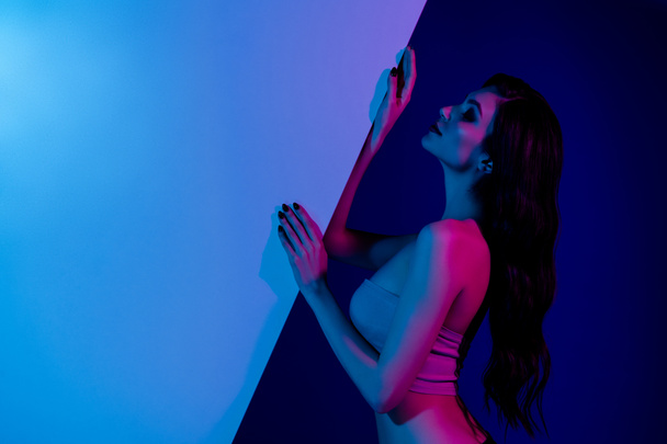 Side portrait of stunning girlfriend at disco party modern event hold blue neon wall advertising inviting clients club. - Foto, immagini