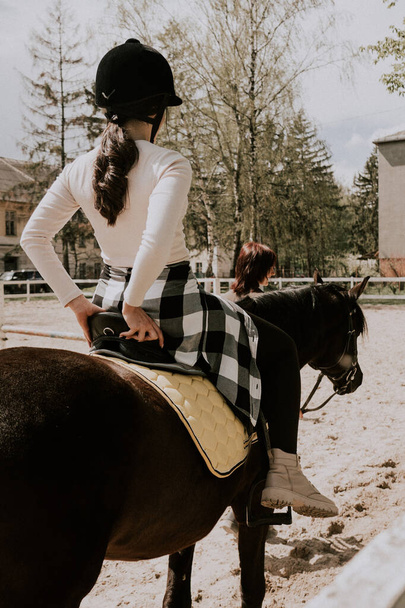 女教師が馬の乗り方を女の子に教えている。乗馬学習乗馬スポーツの練習の女性ライダー。アクティブなライフスタイルとレジャー活動のコンセプト - 写真・画像