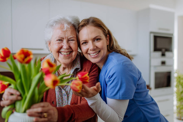Senior woman and nurse with a tulip bouquet. - Zdjęcie, obraz