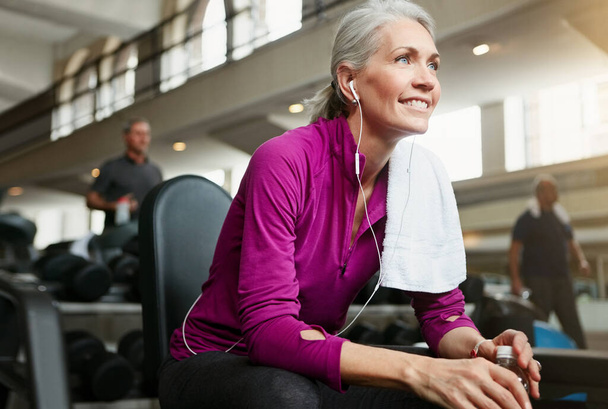 Pihenj, ha kell, aztán folytasd. Portré egy boldog idős nőről, aki szünetelteti az edzést az edzőteremben. - Fotó, kép