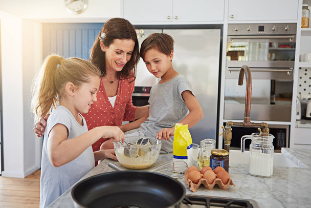 Ukázat jim, jak se dělá jejich oblíbená pochoutka. svobodná matka učí své děti, jak dělat palačinky - Fotografie, Obrázek