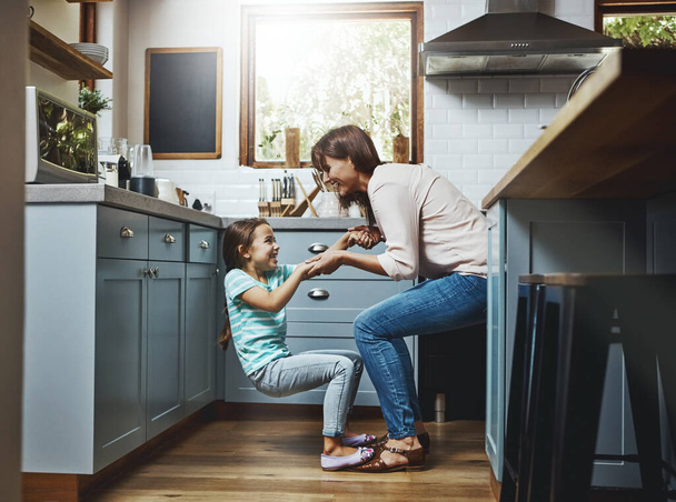 Tienen algunos movimientos geniales. una madre jugando con su hija pequeña en la cocina en casa - Foto, Imagen