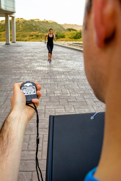 Trainer hand met chronometer met timing vrouw opleiding - Foto, afbeelding