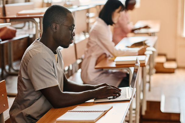 Африканский студент-медик печатает на ноутбуке во время лекции в университете - Фото, изображение