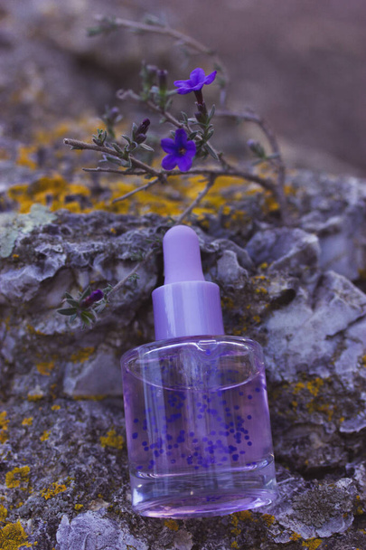 Cosmetic bottle with facial serum. Glass jar with a dropper. Purple cuticle oil with pellets has lavender scent. Beauty treatment concept. Anti aging products. Alternative medicine Copy space for text - Photo, Image