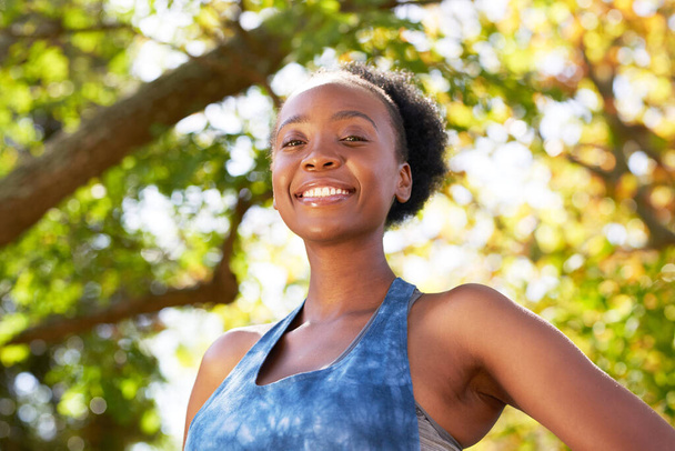 Retrato de una joven mujer negra en ropa deportiva con árboles, parque, sol. Foto de alta calidad - Foto, Imagen