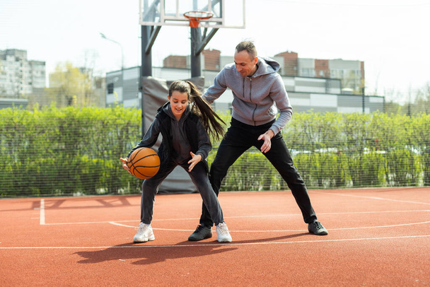 Feliz padre e hija adolescente afuera en la cancha de baloncesto - Foto, imagen