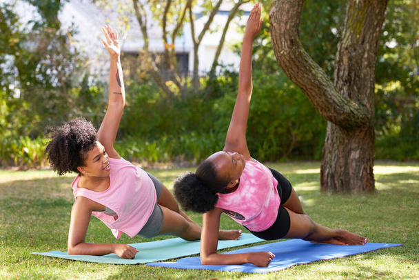 Twee jonge zwarte vrienden doen samen een zijplank in het park, yoga fitness. Hoge kwaliteit foto - Foto, afbeelding